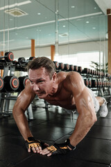 Fit strong man doing diamong push-ups in gym when working out in the morning