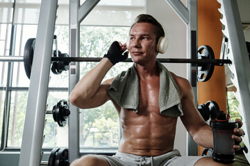 Fit man listening to music when exercising in gym