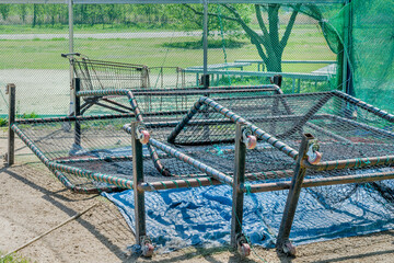 Baseball netted backdrops stacked at home base in urban park.