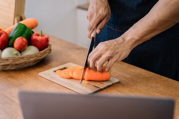 Male prepares cooking healthy food from fresh vegetables and fruits in kitchen room.