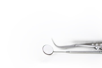 Dental mirror or instrument on white table with blur background and space.Tooth or teeth problem at dental clinic.Orthodontic and Dentistry concept.Dentist tool at clinic or hospital.Tooth extraction.