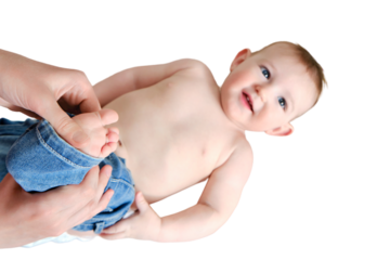 A mother woman puts on jeans pants for a baby boy, isolated on a white background. Mom dresses a happy child in clothes. Kid nine months old