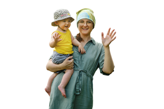 Mother holds a happy toddler baby boy in her arms and waves her hand, isolated on a white background. Smiling child with mom doing hello or bye gesture. Kid age one year