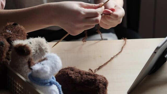 A young woman's hands knit with needles. A favourite hobby, handicraft.