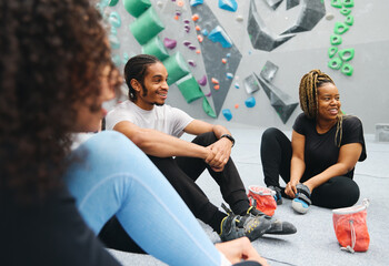 Multi-Cultural Group Watching Friend On Climbing Wall In Indoor Activity Centre