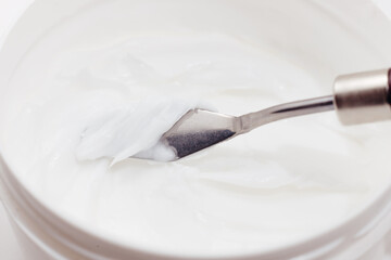 White Face Moisturizing Cream in a Cosmetics Jar taken Sample with Spatula, close-up