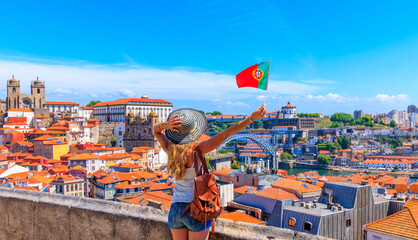 Woman tourist holding portuguese flag in front of panoramic viewpoint of cityscape- Porto,  Portugal