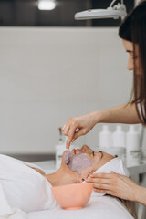 Obraz na płótnie Canvas Cosmetic jelly mask, facial skincare. Cosmetologist applies alginate mask with spatula on face