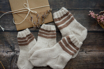 Brown baby socks made of soft cotton yarn, o dark wooden background