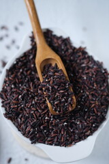 raw black rice in a white ceramic bowl. Black rice is known to have health benefits, has a low glycemic index, low calories, high fiber, making it suitable for a healthy diet. oryza sativa