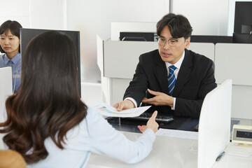 넥타이를 매고 고객에게 설명을 하고있는 은행 직원