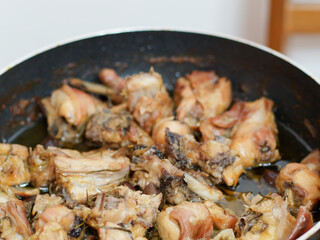 Fried rabbit legs on frying pan with vegetables and herbs