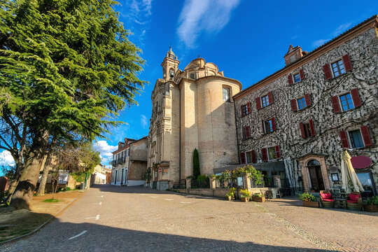 Cobblestone street and catholic church under blue sky in Neive, Italy.