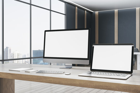 Contemporary designer office desktop with empty white mock up computer screens, supplies and blurry interior with windows and city view background. 3D Rendering.