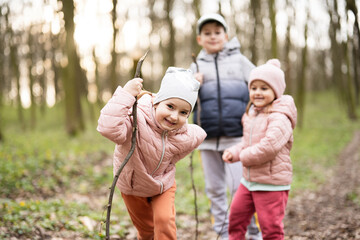 Three kids hiking and discovering spring forest. Happy childhood.