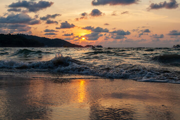 Incredibly picturesque landscape with a view of the waves in the ocean and the bronze sun at the golden hour at sunset in thailand on the island of phuket, patong beach