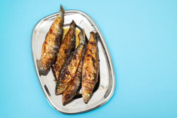 Grilled sardines in metal dish on dark