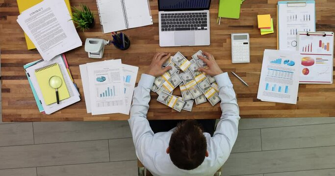 Businessman raking up bunch of money dollars at table in office top view 4k movie. Profitable financial deals in business concept