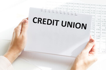 Credit Union text on a notebook in the hands of a businessman against the background of an office desk
