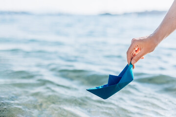 Obraz premium A woman's hand lowers a paper boat into the water