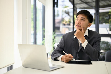 Smart and inspired Asian businessman thinking, planning his business project