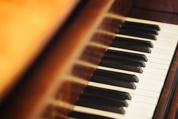 Piano keyboard background. Brown wood style. White and black keys. Instrument play background. Warm color closeup piano. Classical music background. Empty copy space on left.