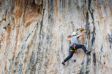 Fototapeta premium Young male climber hanging by a cliff