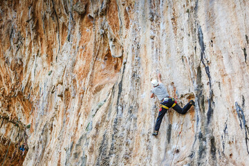 Young male climber hanging by a cliff