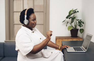 Good music is the ultimate work motivator. a young businesswoman using headphones and a laptop in a modern office.