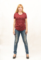 General shot of a beautiful blonde middle-aged woman facing the camera in a photo studio with white background, she is dressed casually in a red T-shirt, blue jeans and black shoes with big heels,
