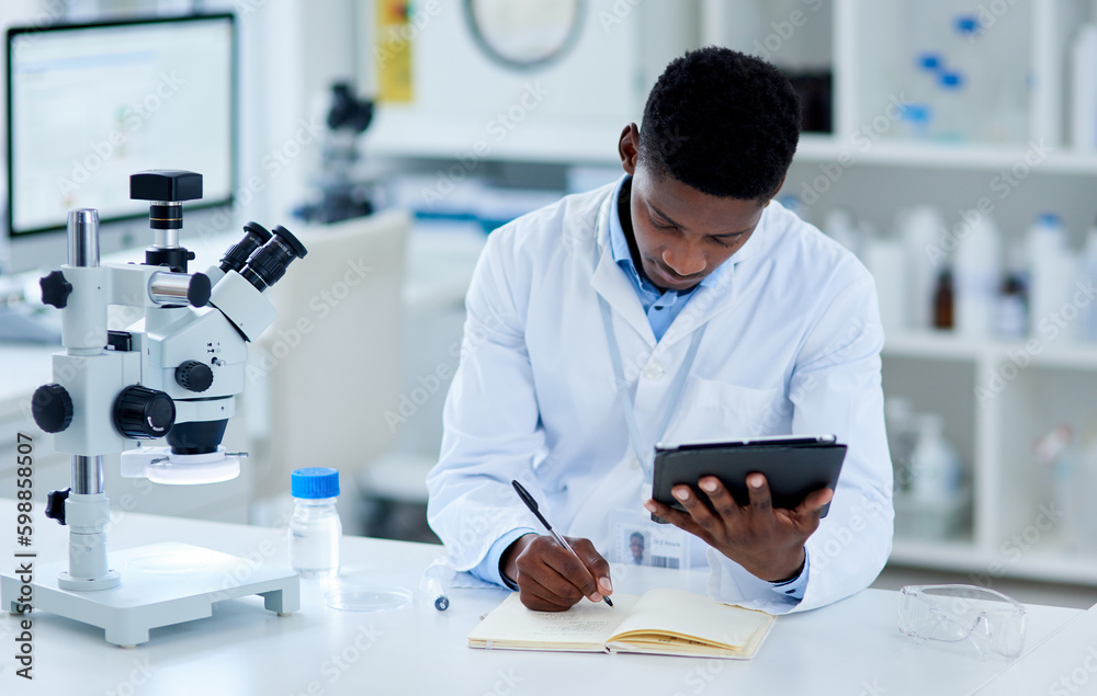 Poster the research is paying off. a focused young male scientist browsing on a digital tablet while making
