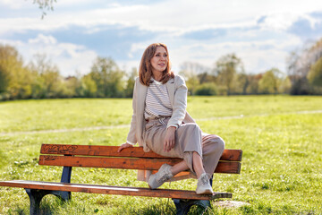 A beautiful middle-aged woman poses in nature on a sunny spring afternoon. The interplay of...