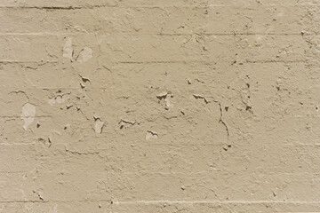 Brick wall painted in a cream color with peeling paint