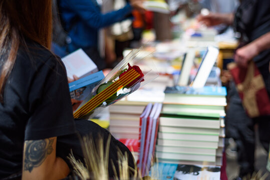 People buyi books while holding red roses during traditional catalan festivity of Sant Jordi celebrations in the city center.