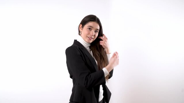 Elegantly dressed young female against white background smiling and stroking her long dark hair while dreamily looking at the camera and to the side  Generative AI