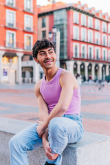 Authentic person smiling outdoors. Carefree gay guy sitting outdoors.