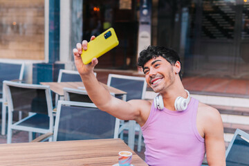 Young hispanic man smiling confident while making selfie by mobile phone in the street