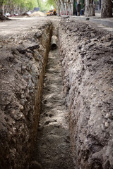 Vertical photo excavated trench on the road in the city for the reconstruction of the water supply.