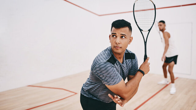 Play it to win it. two young men playing a game of squash.