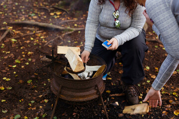 Women setting up fire on rustic camping stove