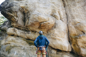 Strong climber with equipment on a belt holding rope and preparing to climb