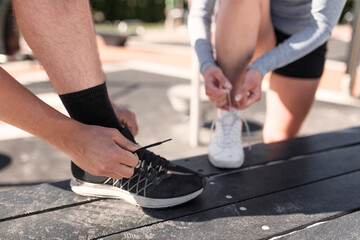 Friends tying sports shoes outdoors