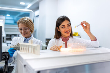 Close up of young doctor in biochemistry analysing and holding test tube with sample of genetic...