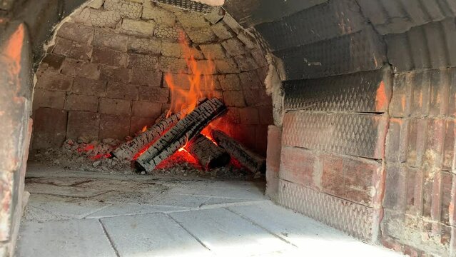 Cooking real pizza in a brick oven. Wood and fire are burning in the stove.