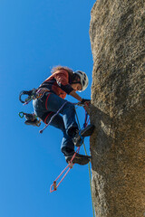 Fototapeta premium Young adult climbing a granite wall at Torrelodones, Madrid. Rock climbing. Extreme sports concept
