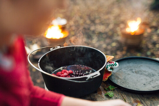 Person preparing berry compote outdoors