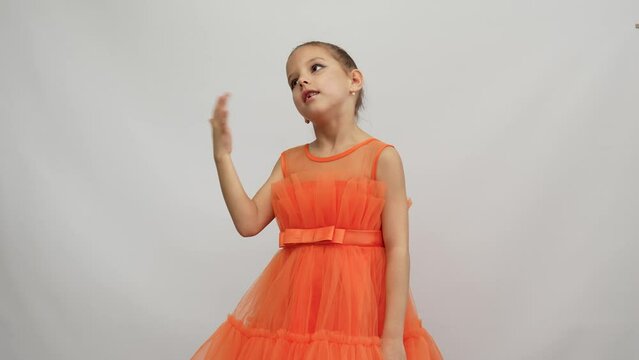 Cute little girl in orange dress posing over white background
