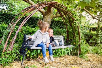Two sisters sitting on bench in garden
