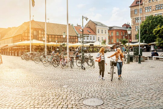 Two female friends walking in city with bicycle