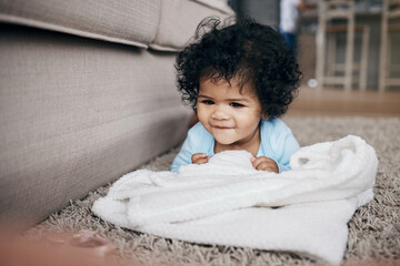 Keeping her entertained with the small things. an adorable little girl lying on the living room floor at home and playing with the laundry.